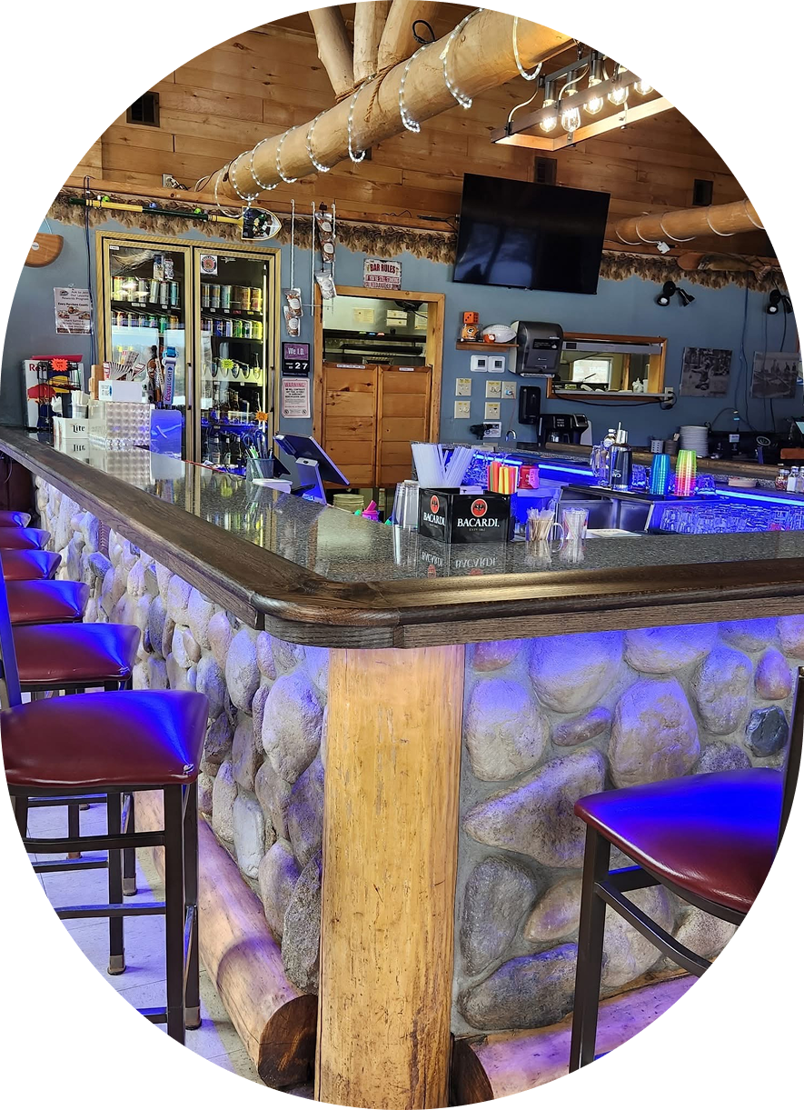 Cozy bar with stone accents and purple cushioned stools under warm lighting.