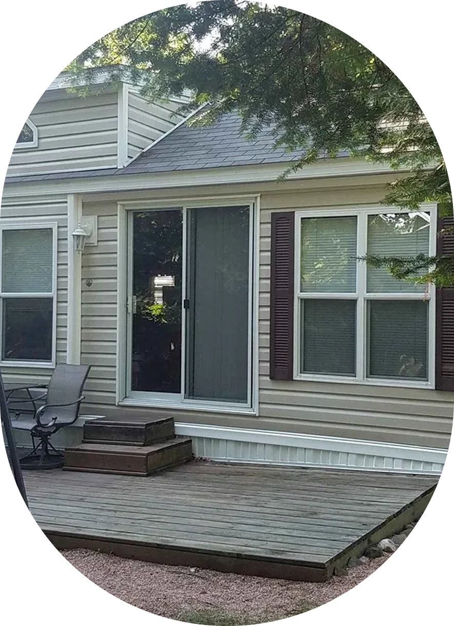 A cozy house entrance with sliding glass doors and a small wooden deck.
