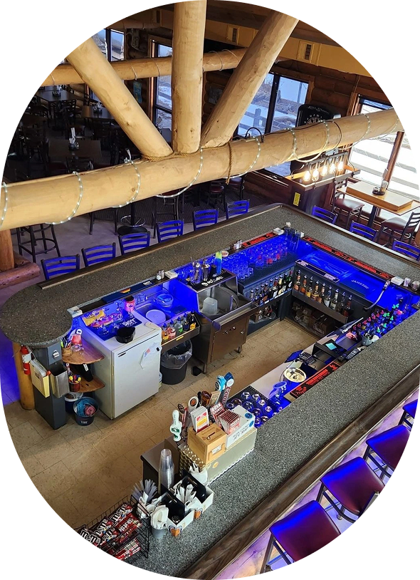 A vibrant bar area with blue lighting and wooden beams overhead.